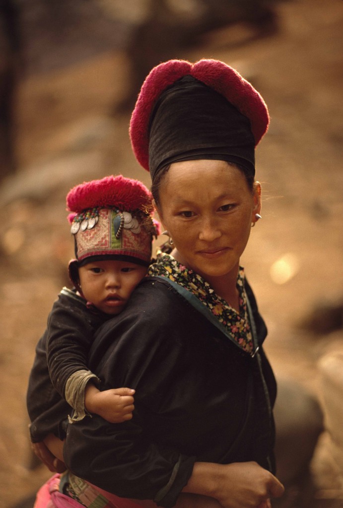 W.E. GARRETT, Una donna hmong e suo figlio con il copricapo tradizionale. Laos 1974